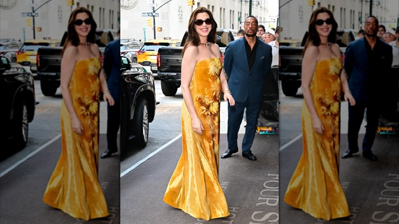 Anne Hathaway smiles in a yellow, strapless dress