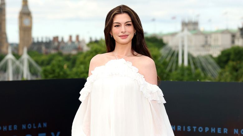 Anne Hathaway smiles in an off-the-shoulder white dress