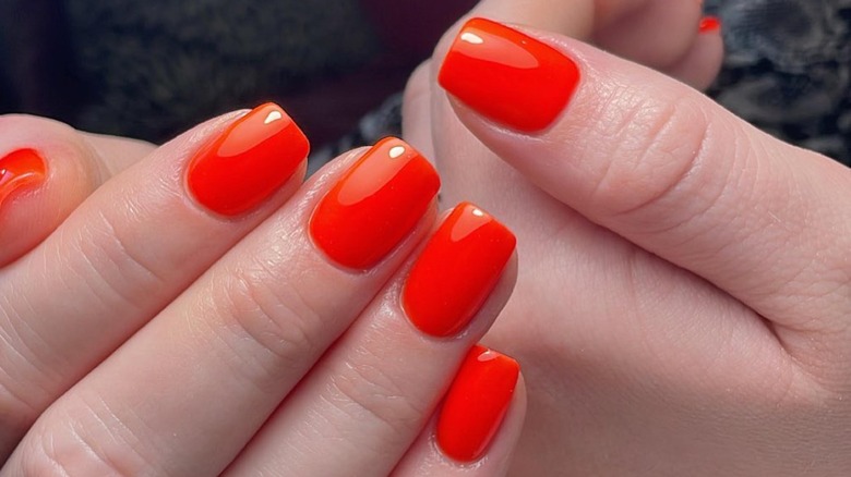 fingers with neon orange manicure