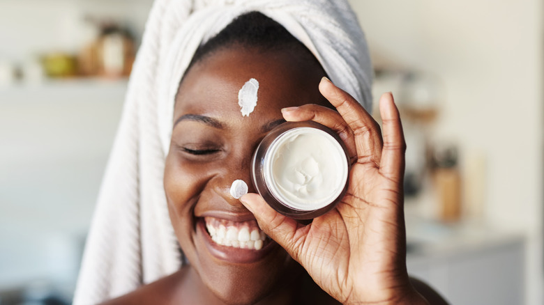 Young woman posing with moisturizer jar