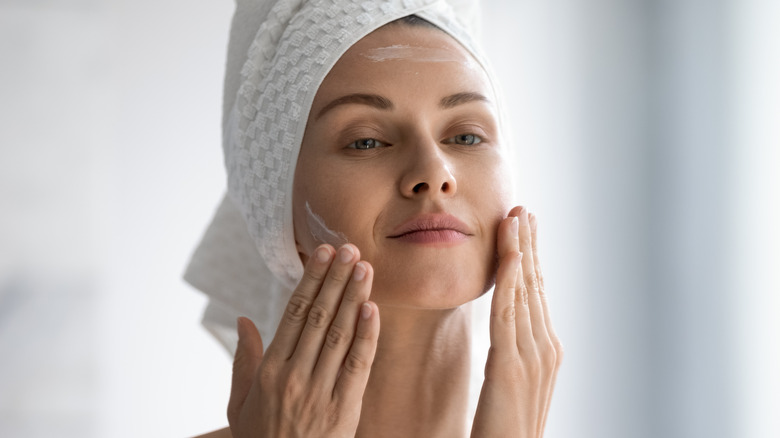 woman applying cream on face