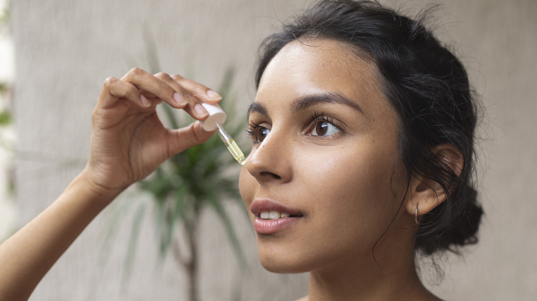 woman adding oil to face