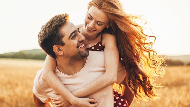 Young couple in sunny field flirting