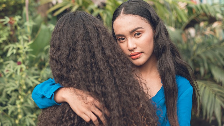 Unsmiling woman hugging friend