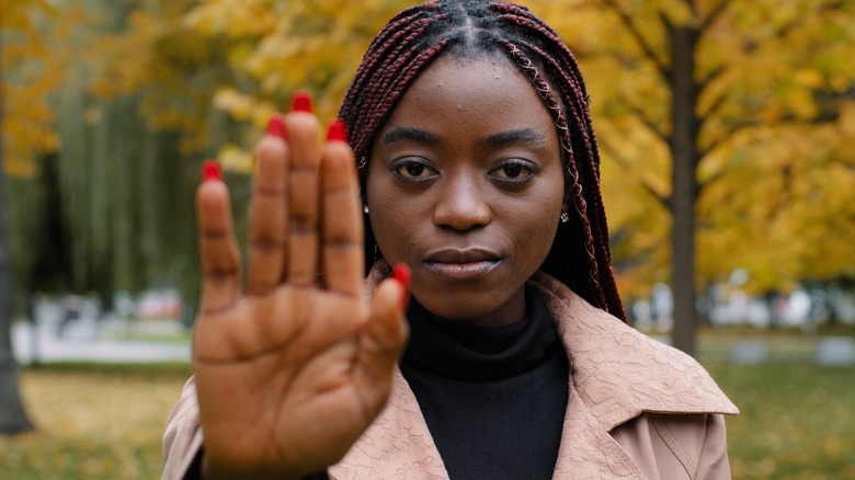 Serious woman holding hand out
