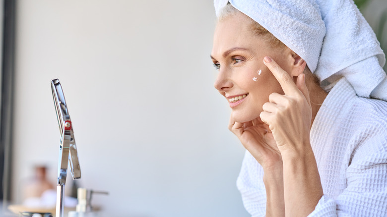 woman applying skincare in mirror