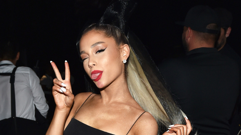 Ariana Grande posing in a black dress and a ponytail