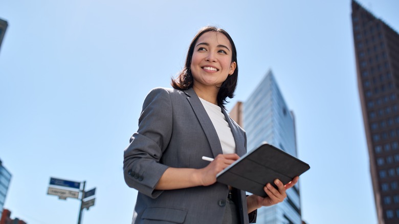 smiling businesswoman in front of skyscrapers