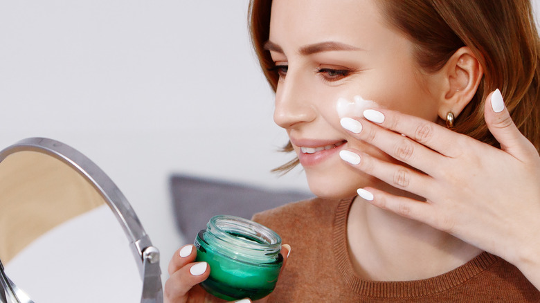 woman putting cream on face