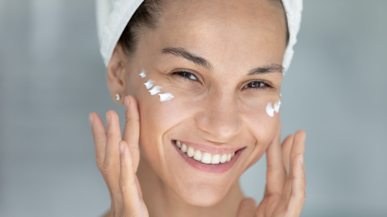 smiling woman applying eye cream