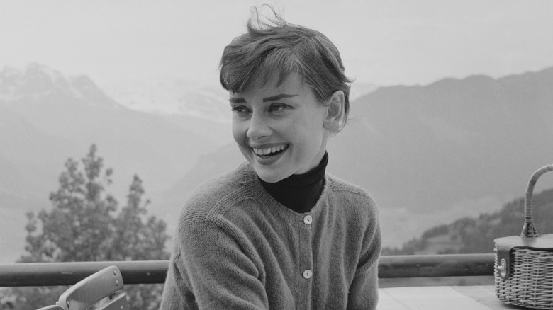 Black and white photo of Audrey Hepburn at a mountaintop restaurant in Switzerland in 1955.