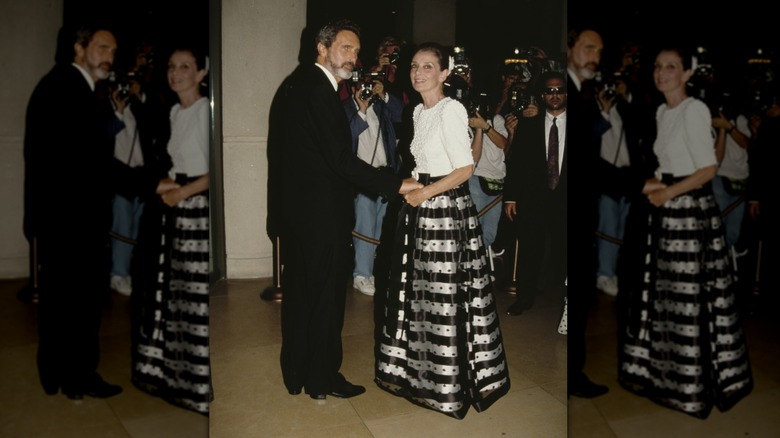 Audrey Hepburn at an event wearing a white top and black-and-silver striped full skirt.