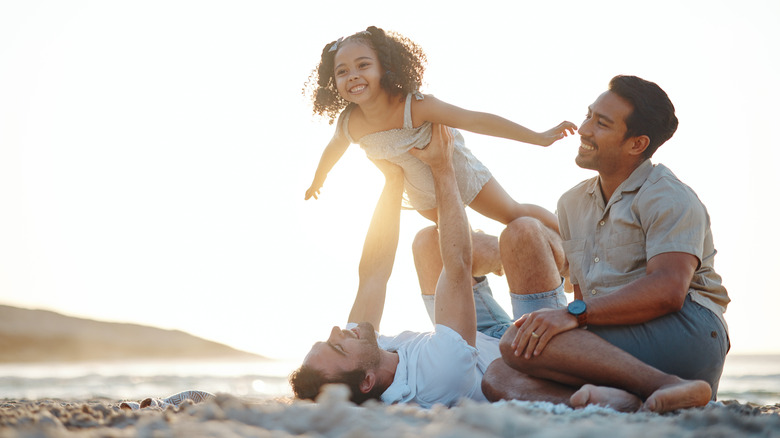 Family playing on beach at sunset, airplane games and island holiday together