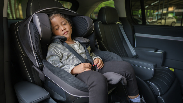 Preschool child girl sitting and sleeping in the car seat, safety baby chair travelling