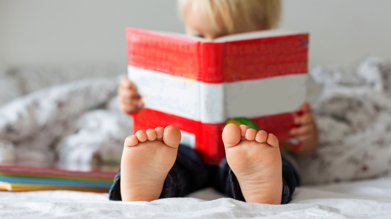 A photo shows a child out of focus while reading a red and white striped book