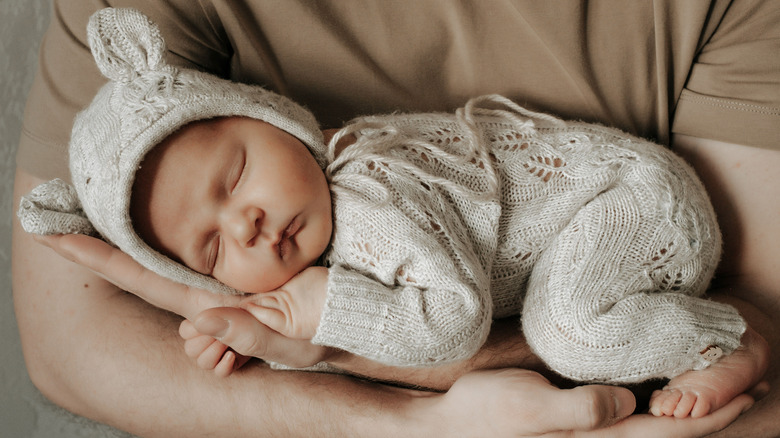 A baby sleeping in her father's arms