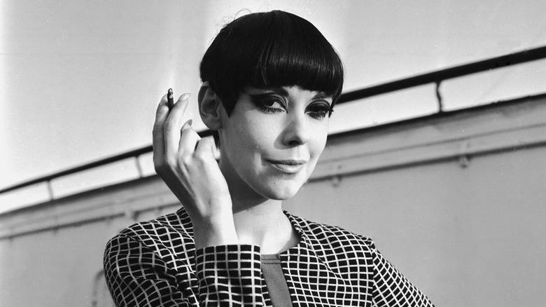 Peggy Moffitt smiles holding a cigarette in 1965