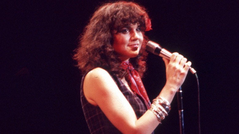 Linda Ronstadt in the 1970s performing on stage wearing a bandana around her neck