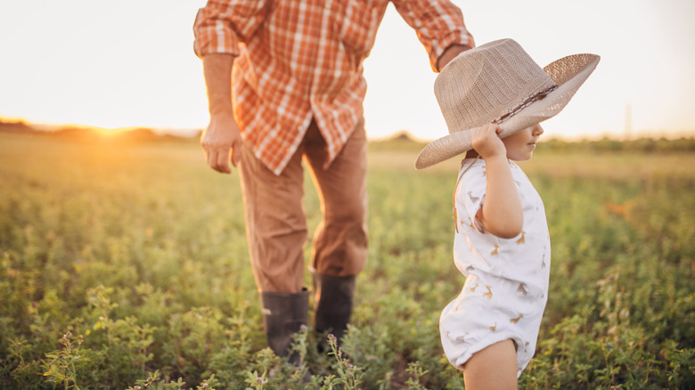 A baby wearing a cowboy hat in a field