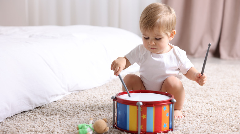 A baby playing with a toy drum