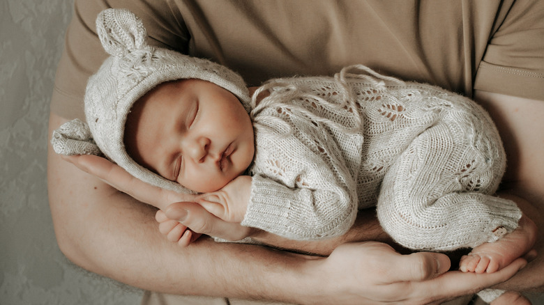 Someone holding a baby in a onesie