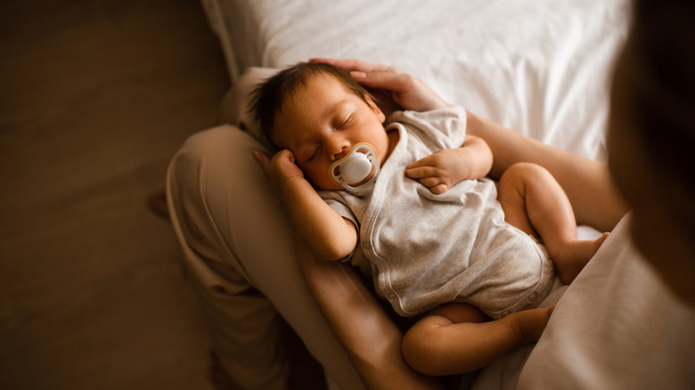 A baby lying in its mom's lap
