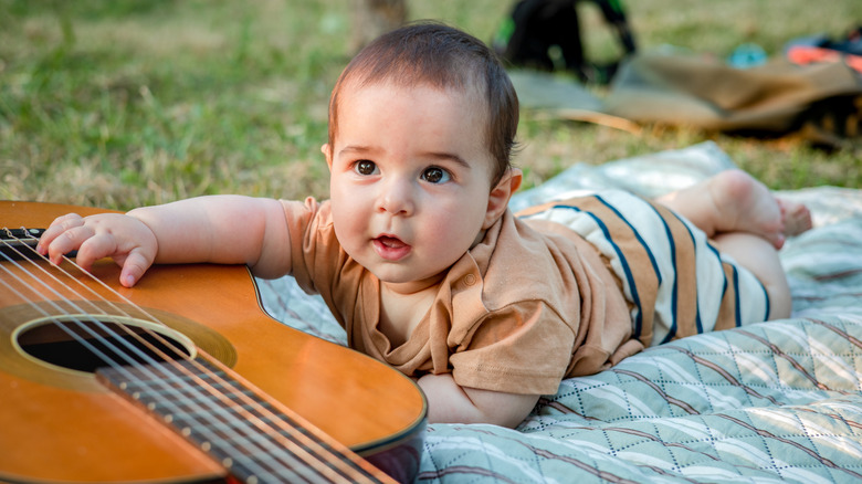 A baby crawling towards a guitar