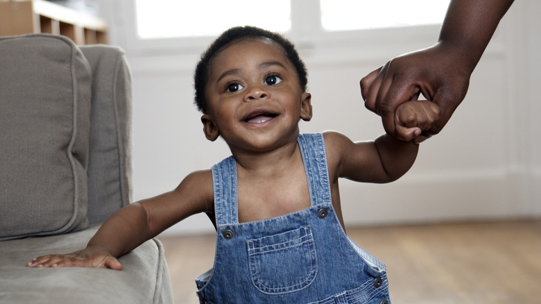 A smiling baby boy in overalls