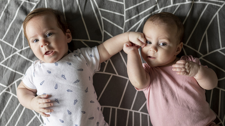 A baby boy and a baby girl together on a blanket