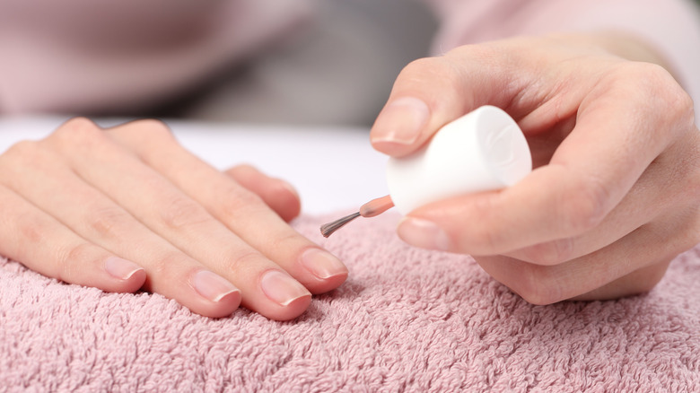 Person about to paint their nails with a pink shade
