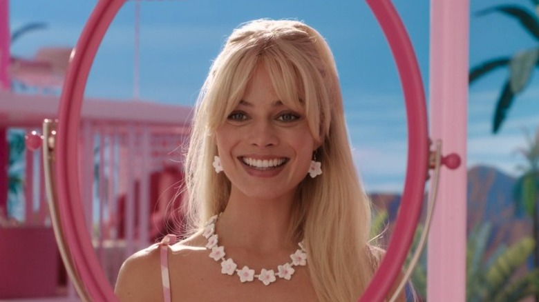 Margot Robbie smiling at herself in the mirror as Barbie
