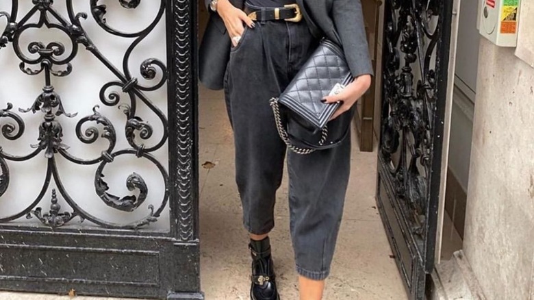 woman walking out of a hotel in barrel-leg jeans