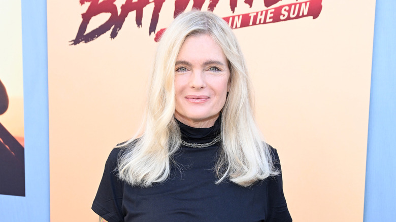 Erika Eleniak at an event in 2024 wearing a black mock turtleneck top with a simple necklace.