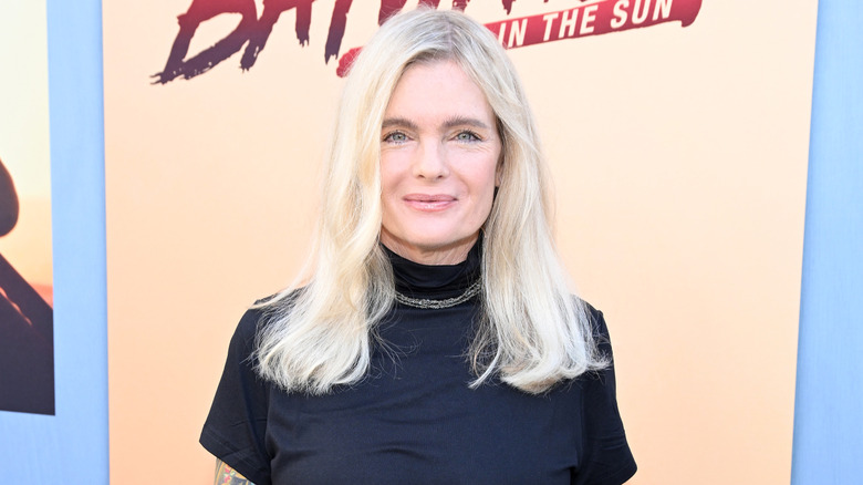 Erika Eleniak at an event in 2024 wearing a black mock turtleneck top with a simple necklace.