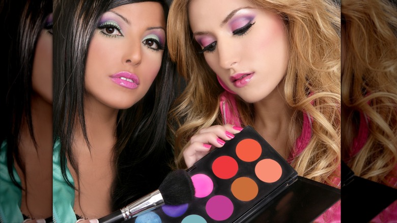 Two women showing off colorful eyeshadow application and palette '80s style