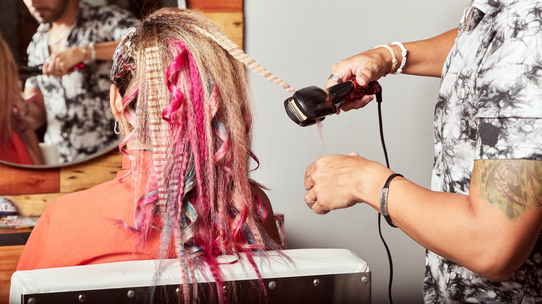 A stylist crimping colorful hair