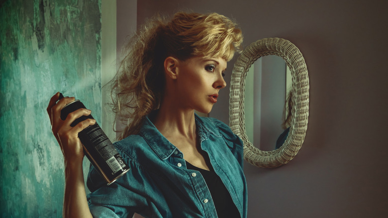An '80s looikng woman spraying hairspray