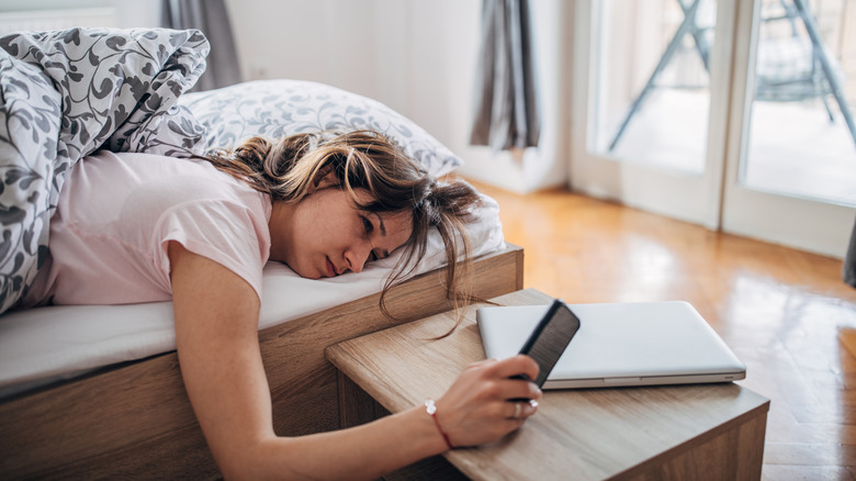 woman lying in bed with phone
