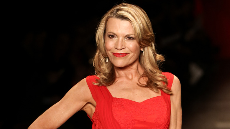 Vanna White wearing a red dress with red lipstick against a black background.