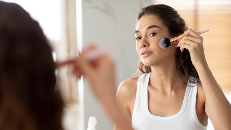 Woman putting on makeup in mirror