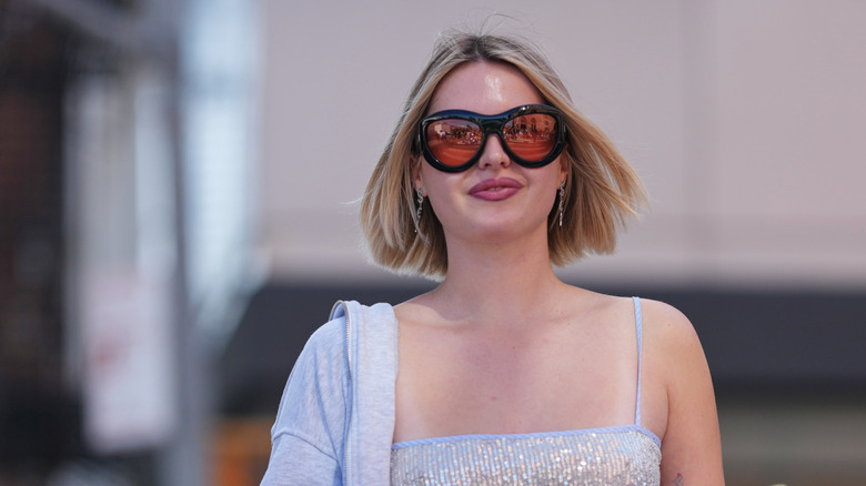 Woman with an Italian bob walking while wearing sunglasses