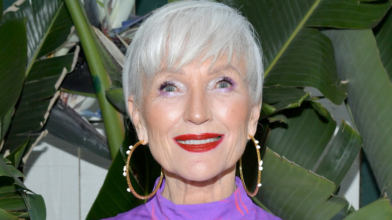 A woman with wavy gray hair wearing colorful makeup