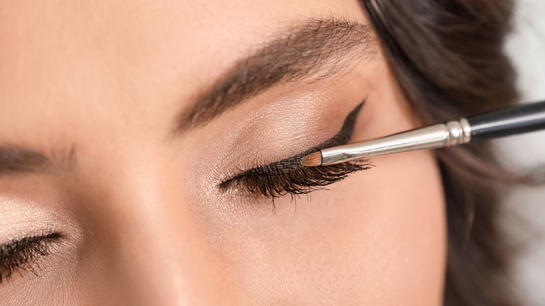 woman applying cat-eye makeup