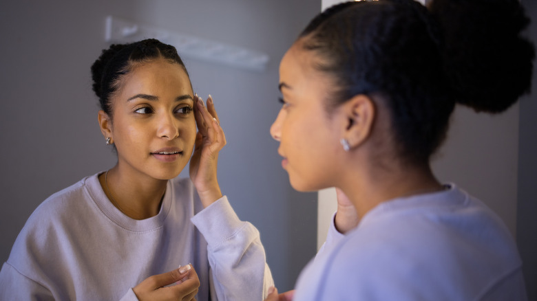 Woman inspecting skin in mirror