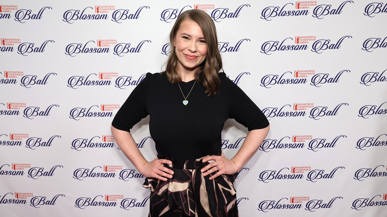 Bindi Irwin poses with her hands on her hips, wearing a black top at the Blossom Ball