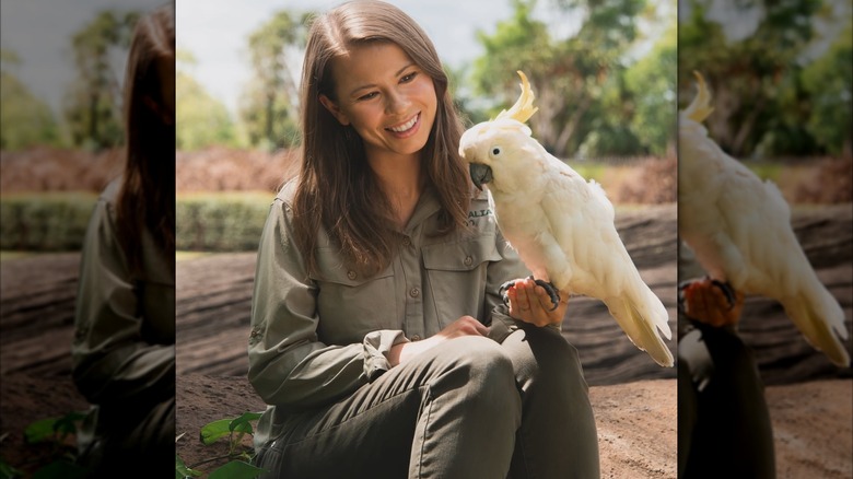 Bindi Irwin in all khaki, holding a bird at the Australia Zoo.