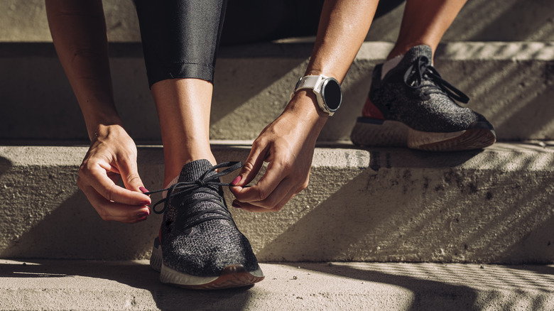 Woman tying laces on black sneakers