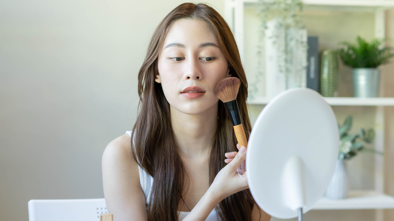 Woman applying blush with makeup brush