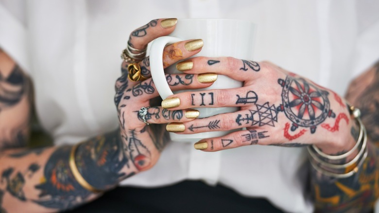 Woman's tattooed hands holding mug
