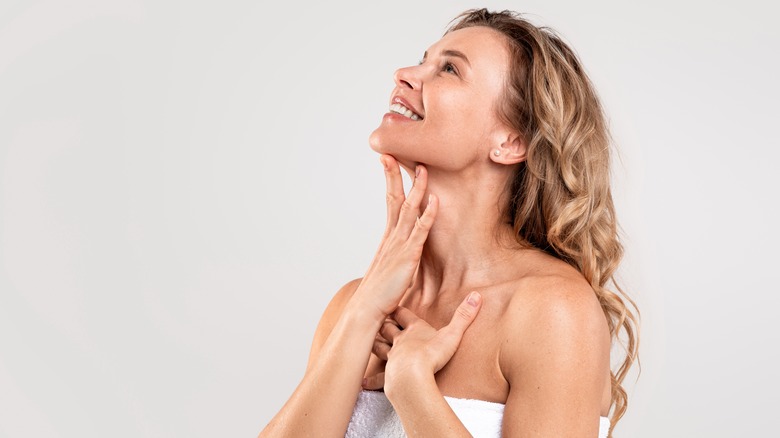 Woman applying skincare to neck.